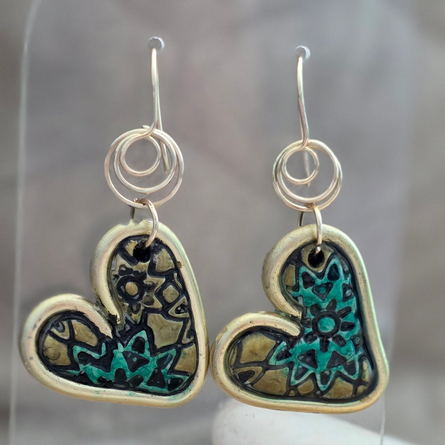 Heart-shaped earrings with intricate designs on a neutral background