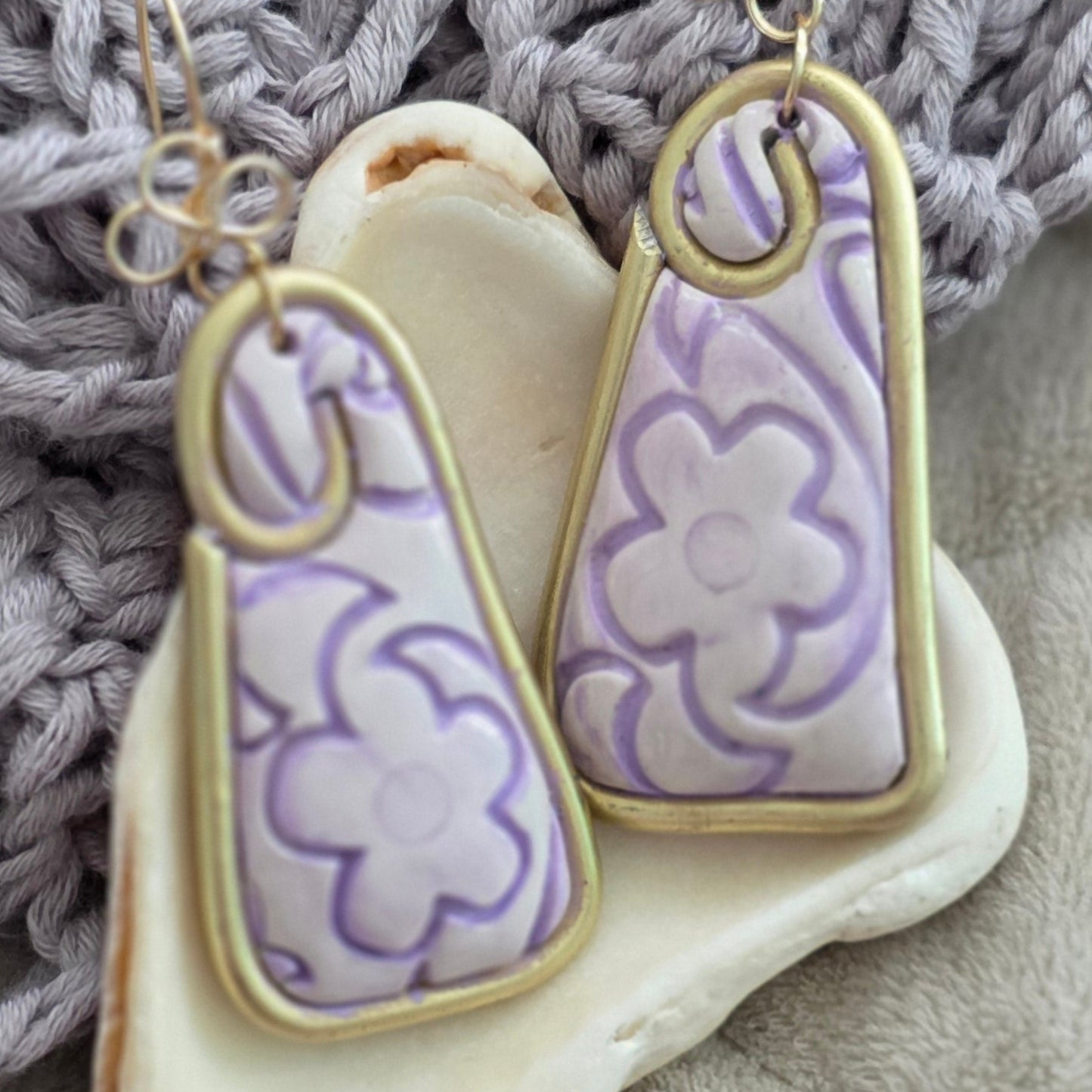 Aretes hechos a mano en polymer clay con diseño floral pintado a mano en tonos lila. Joyería artesanal única, ligera y elegante de la colección Singular.