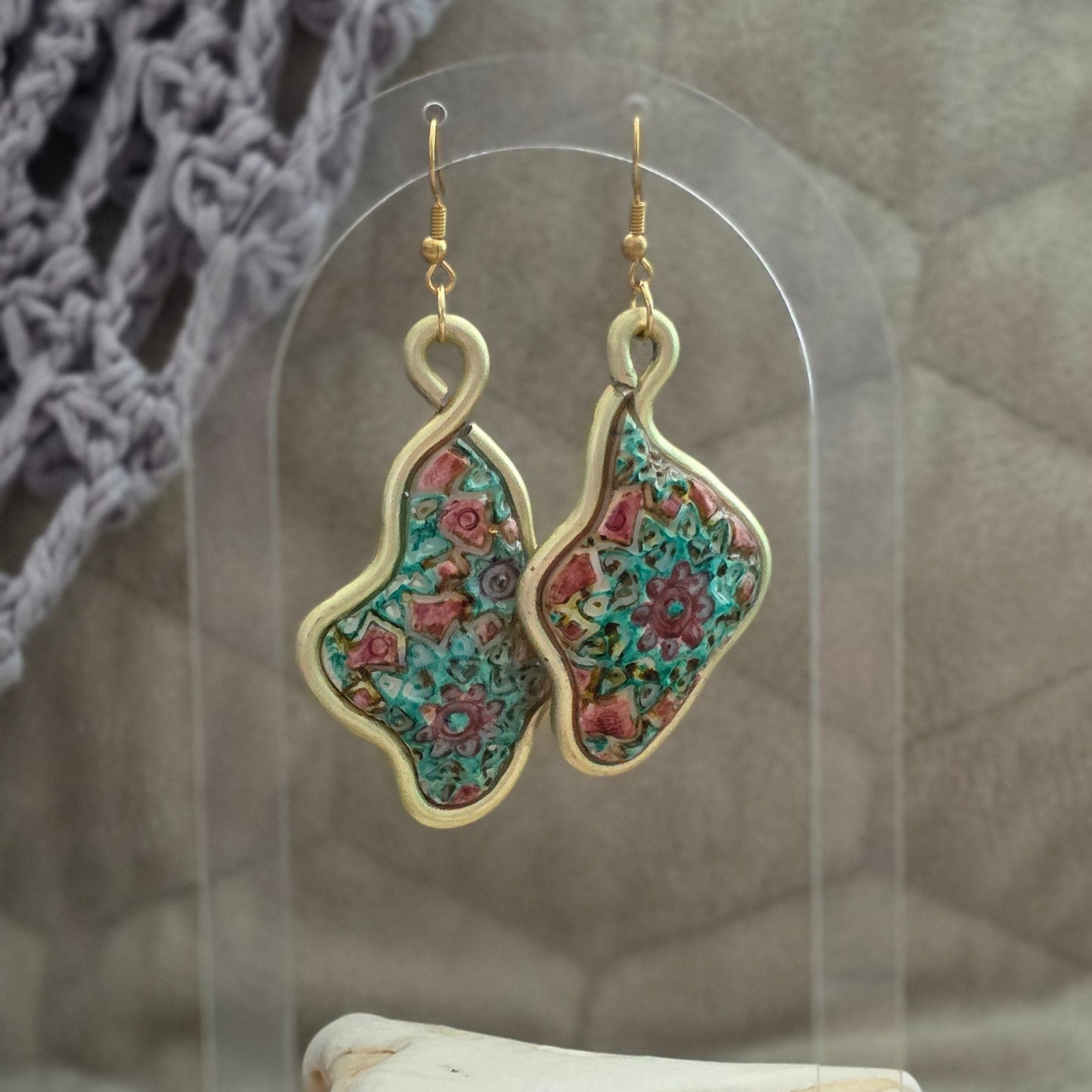 Aretes artesanales en polymer clay con diseño floral en tonos verdes y rosados, enmarcados en alambre. Joyería única, ligera y elegante de la colección Singular.