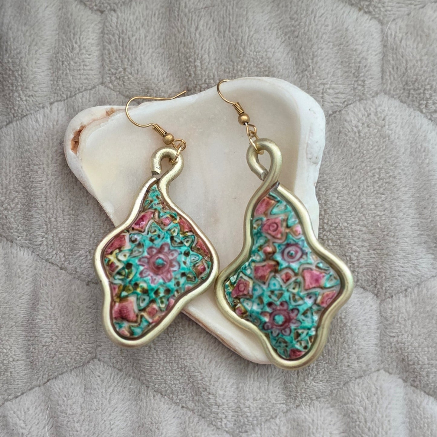 Aretes artesanales en polymer clay con diseño floral en tonos verdes y rosados, enmarcados en alambre. Joyería única, ligera y elegante de la colección Singular.
