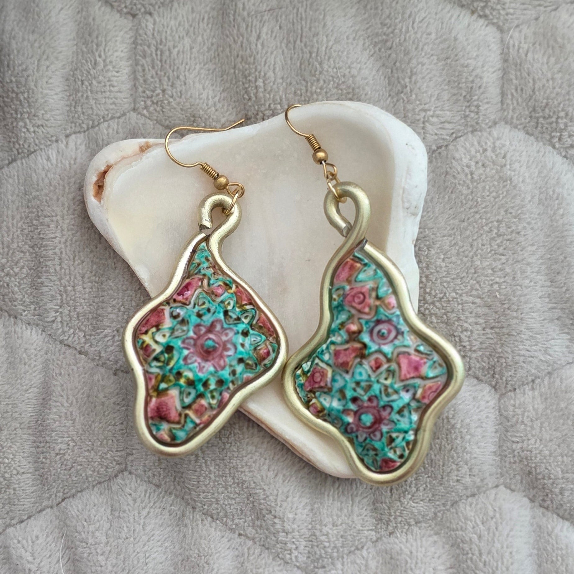 Aretes artesanales en polymer clay con diseño floral en tonos verdes y rosados, enmarcados en alambre. Joyería única, ligera y elegante de la colección Singular.