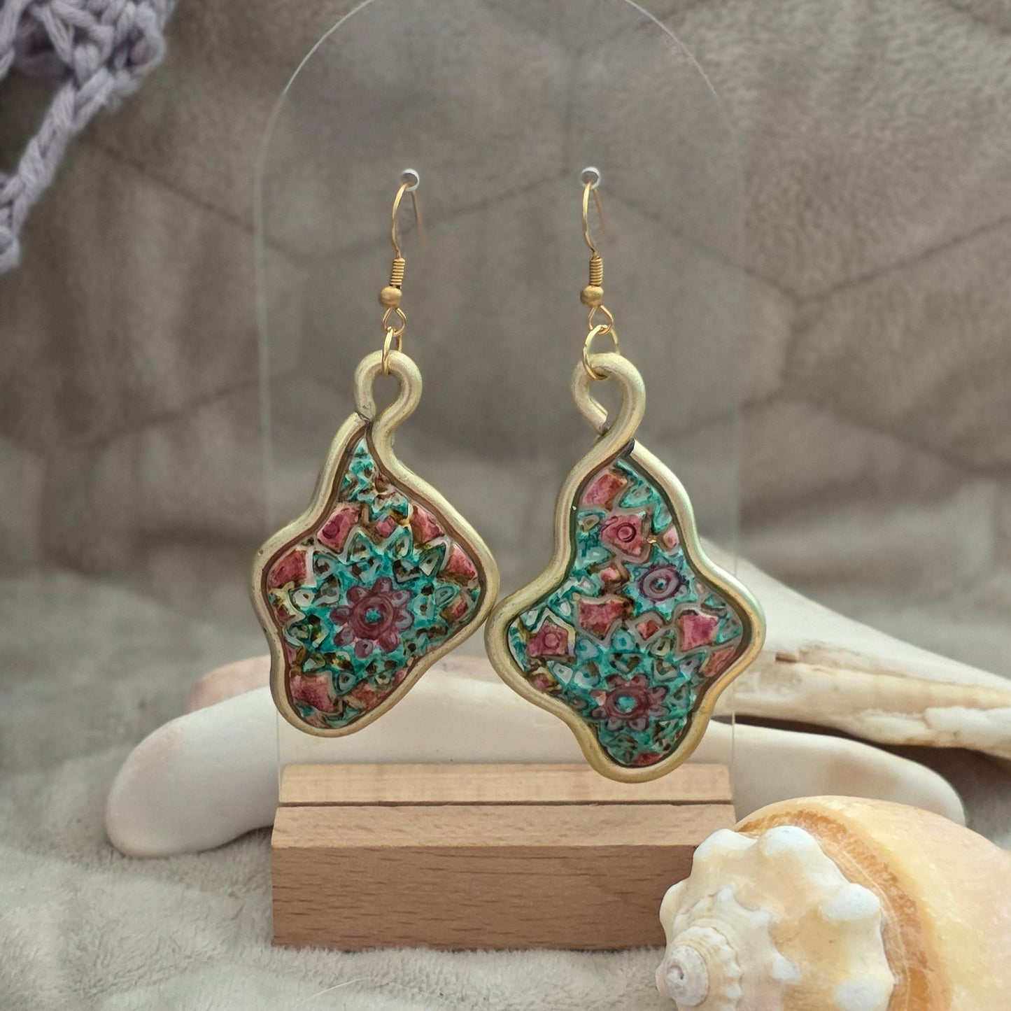 Aretes artesanales en polymer clay con diseño floral en tonos verdes y rosados, enmarcados en alambre. Joyería única, ligera y elegante de la colección Singular.