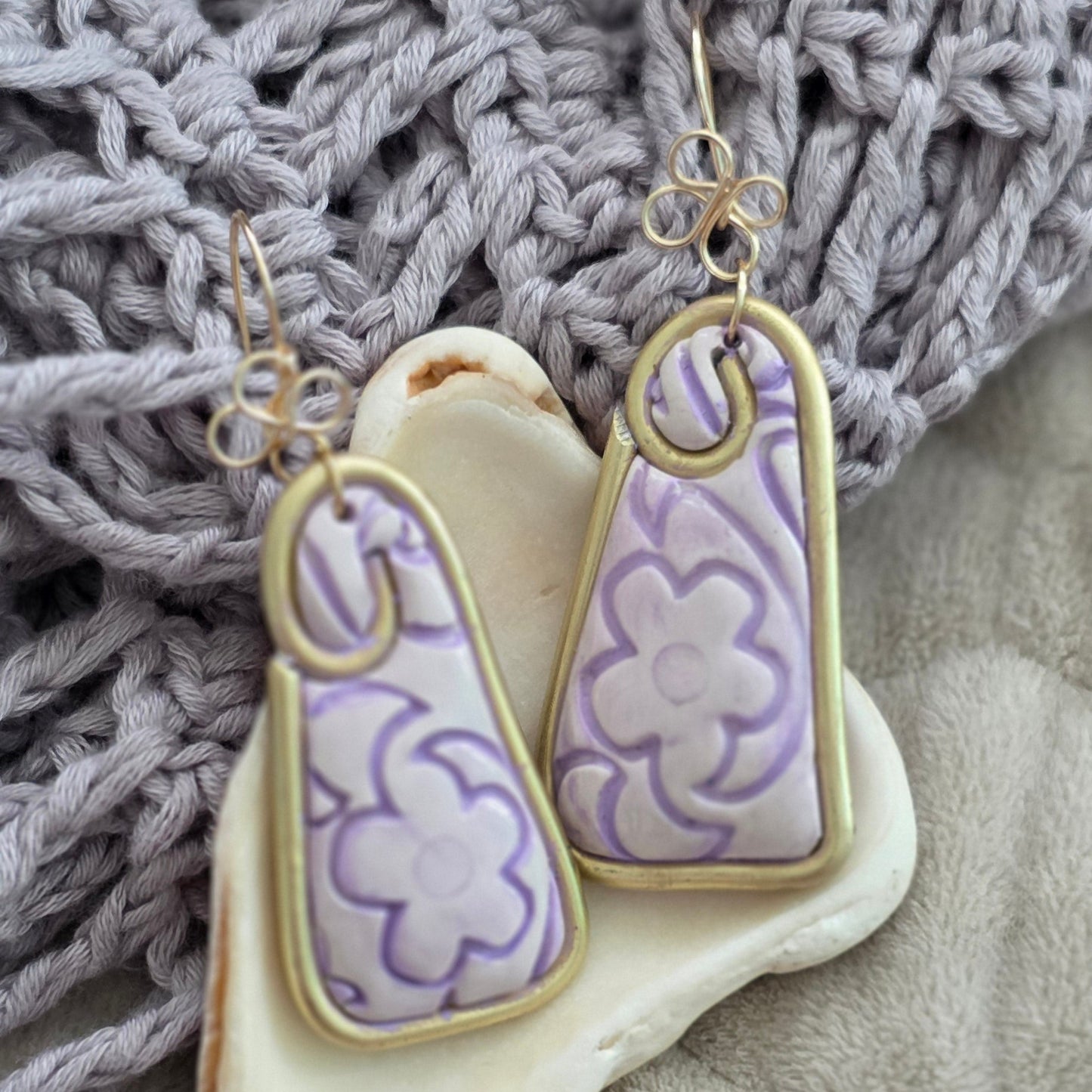 Aretes hechos a mano en polymer clay con diseño floral pintado a mano en tonos lila. Joyería artesanal única, ligera y elegante de la colección Singular.