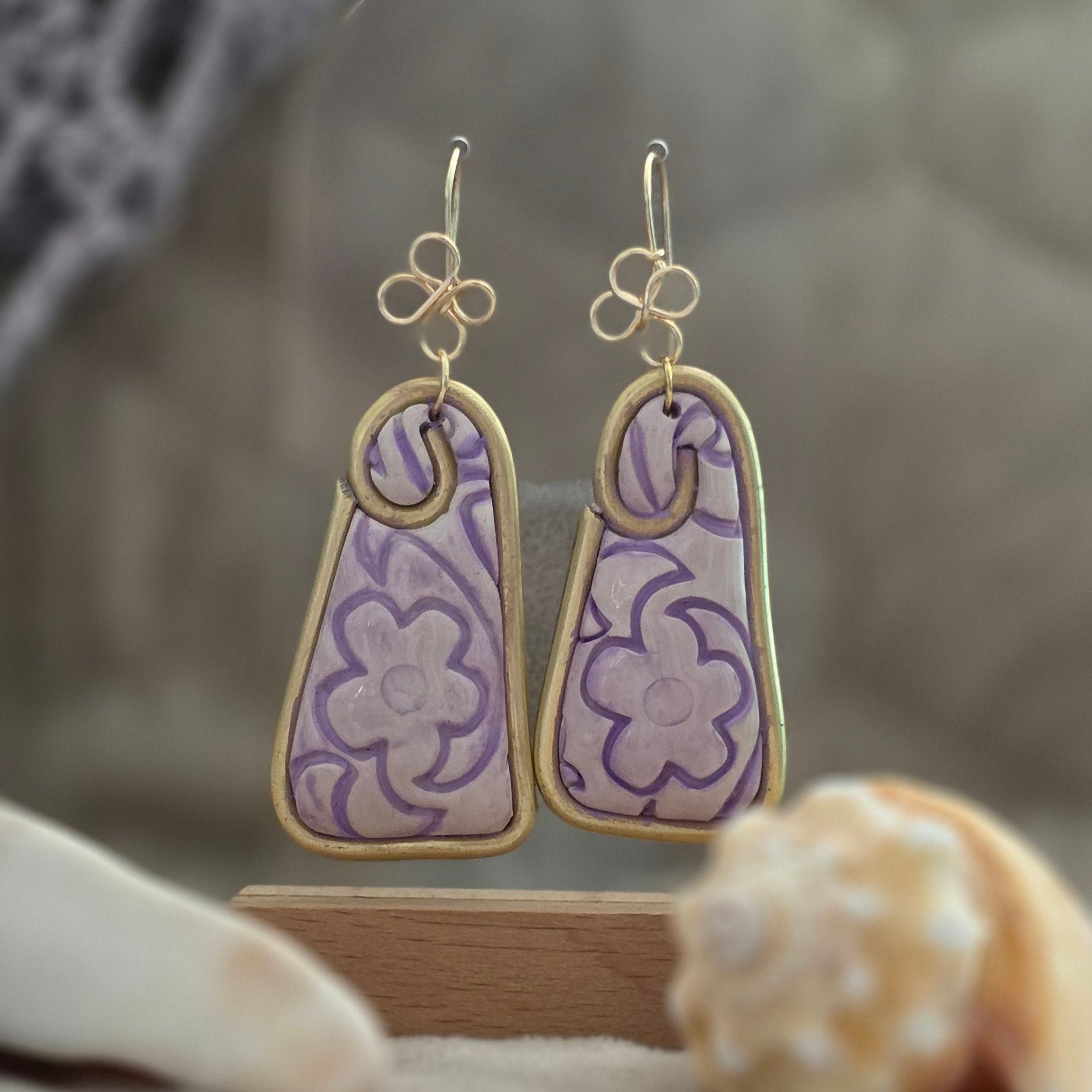 Aretes hechos a mano en polymer clay con diseño floral pintado a mano en tonos lila. Joyería artesanal única, ligera y elegante de la colección Singular.