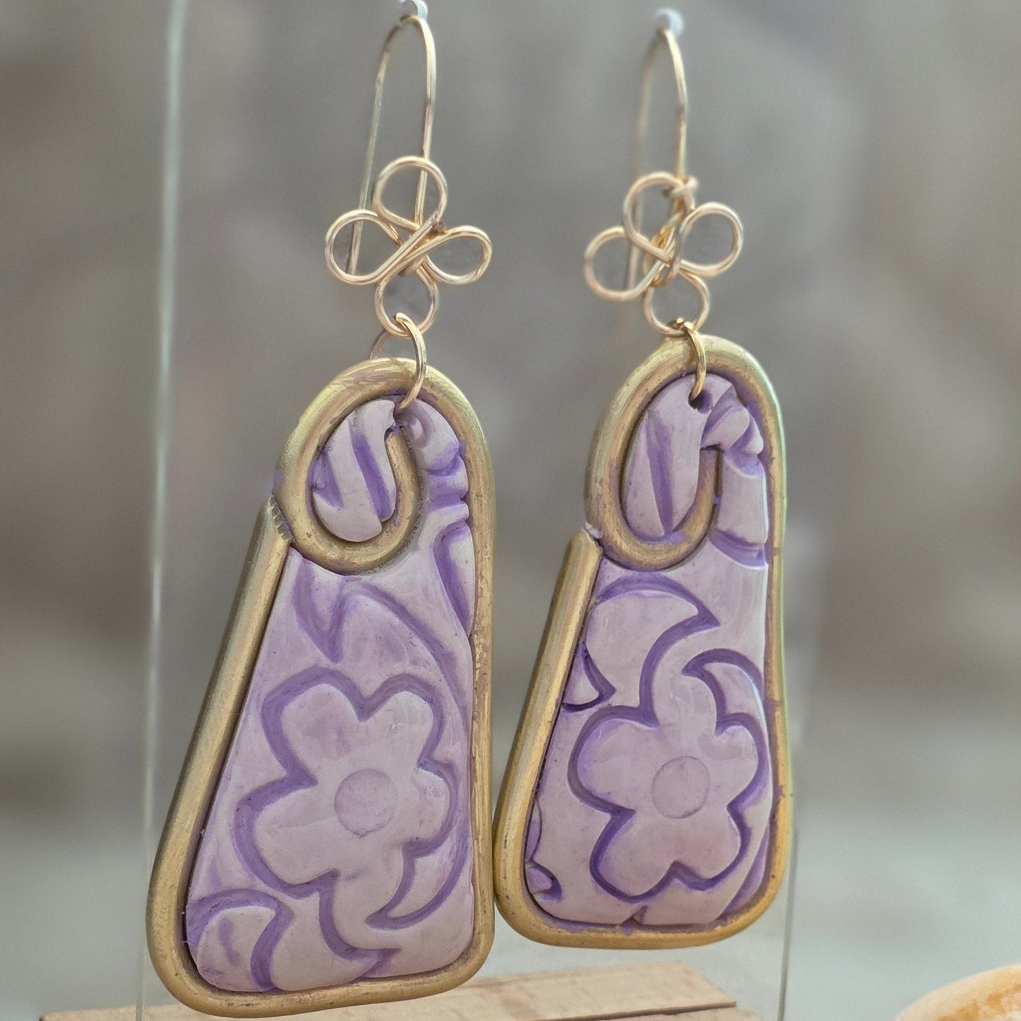 Aretes hechos a mano en polymer clay con diseño floral pintado a mano en tonos lila. Joyería artesanal única, ligera y elegante de la colección Singular.