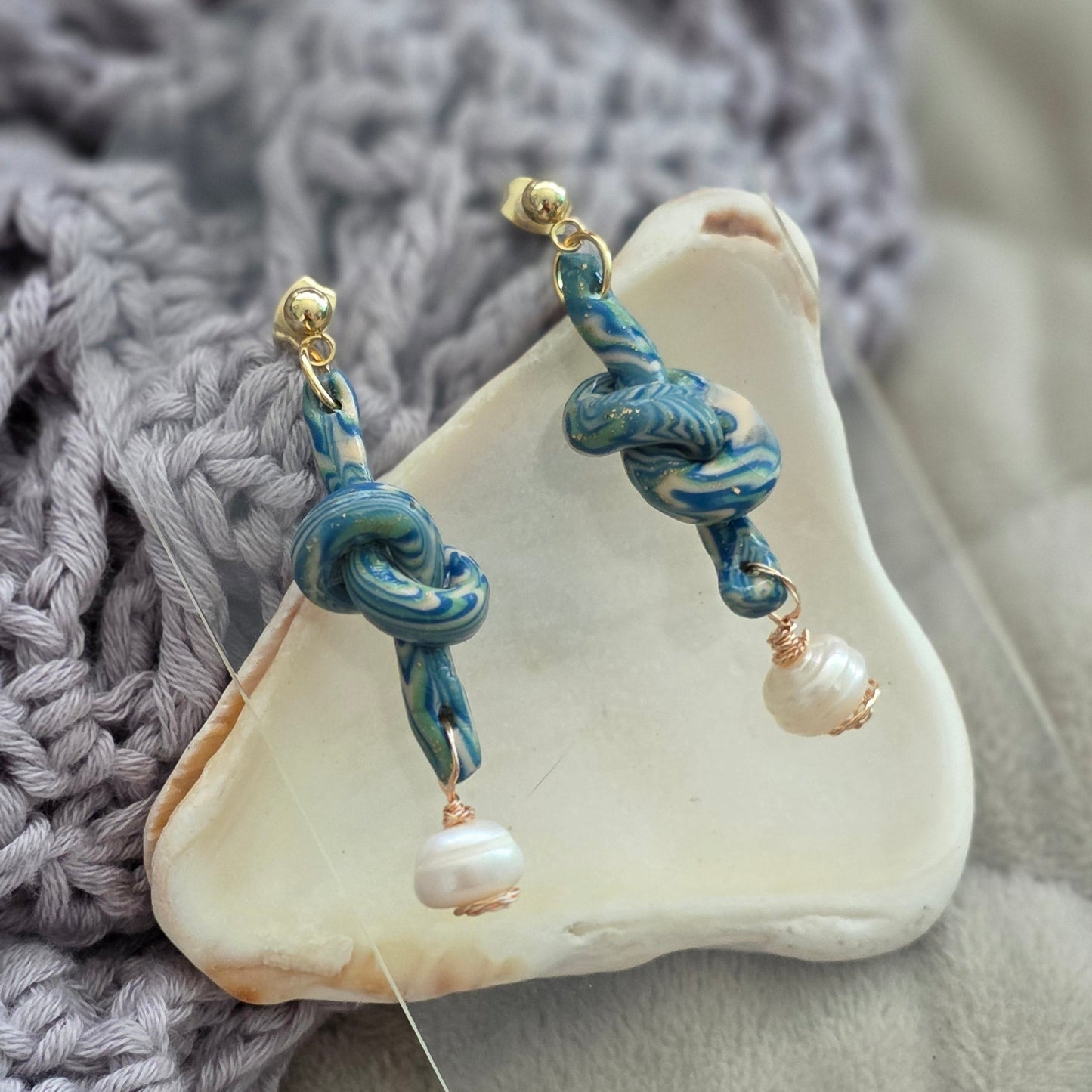 Aretes hechos a mano en polymer clay marmolizado con diseño de nudo y perla natural. Joyería única, elegante y ligera de la colección Singular.
