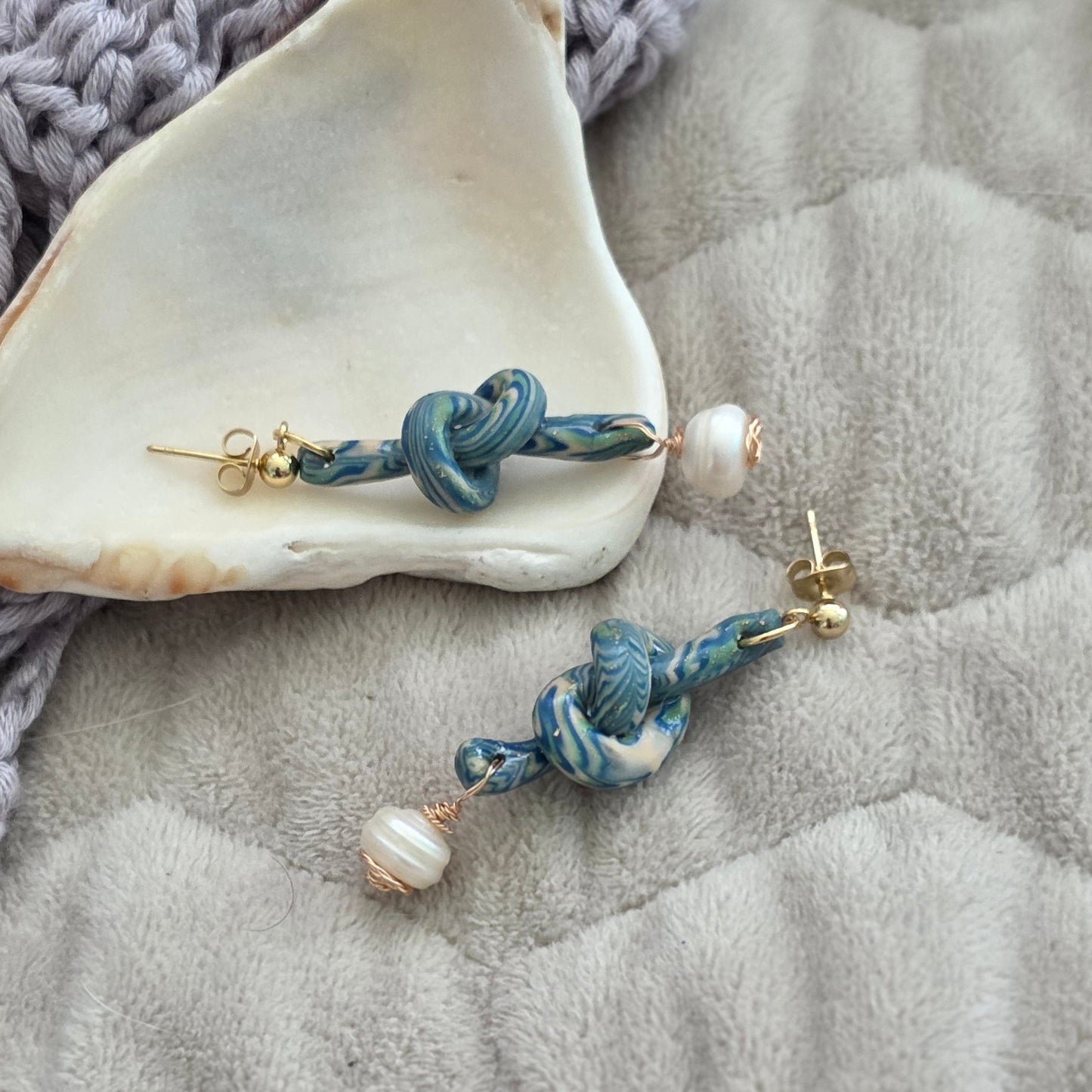 Aretes hechos a mano en polymer clay marmolizado con diseño de nudo y perla natural. Joyería única, elegante y ligera de la colección Singular.