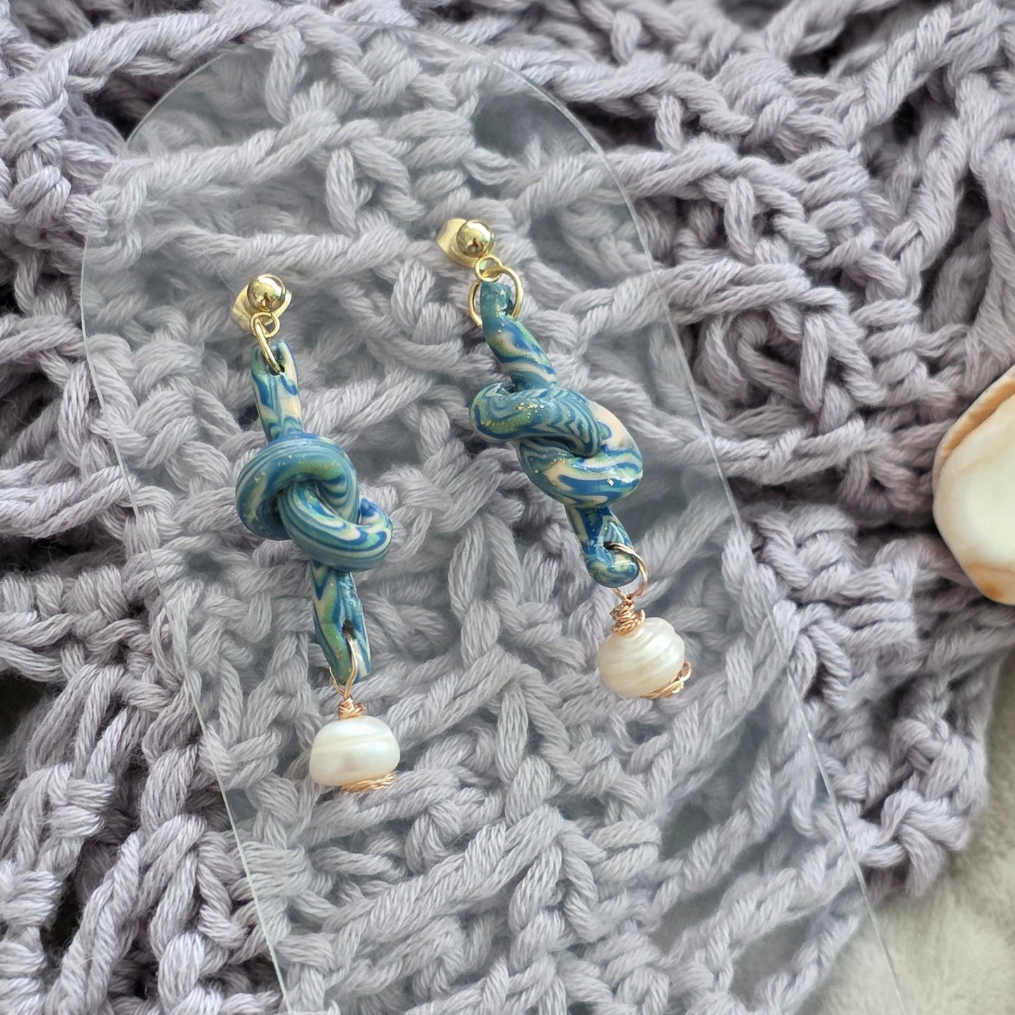 Aretes hechos a mano en polymer clay marmolizado con diseño de nudo y perla natural. Joyería única, elegante y ligera de la colección Singular.